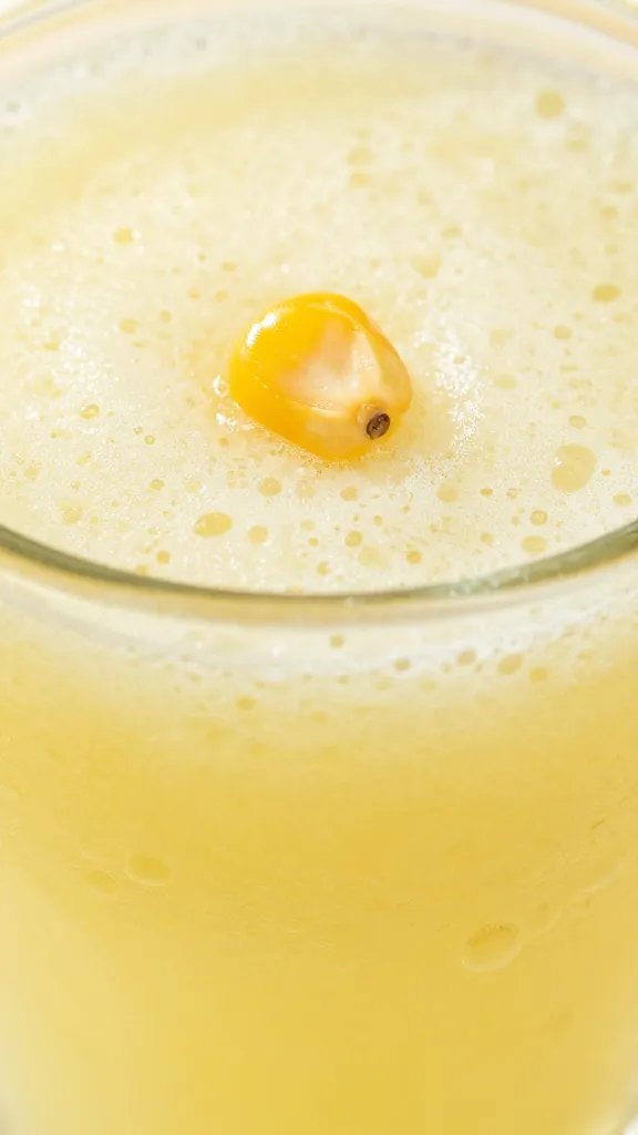 Closeup of a single corn kernels glistening in lemonade slush glass